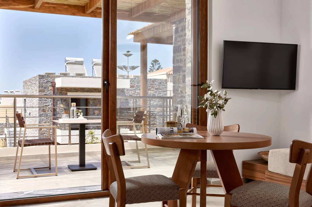 Dining table by floor-to-ceiling glass doors opening onto a furnished terrace with village views