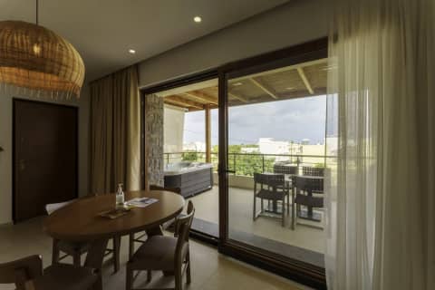 Dining area with rattan pendant lamp opening to a covered balcony with hot tub and views over Gouves, Crete