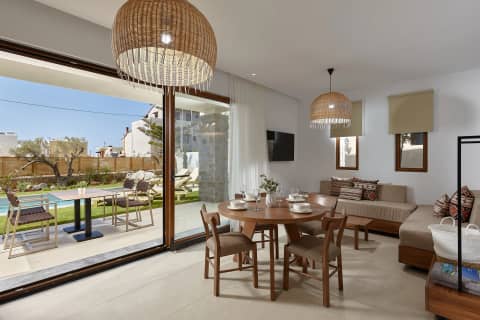Bright open-plan living and dining room with rattan pendants, sliding glass doors to the garden and private pool