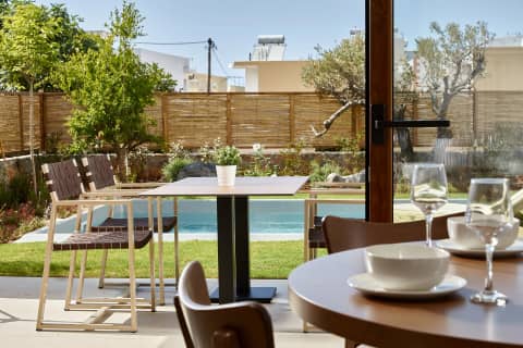 View from the dining table across the garden to the private pool and olive trees at Volta in Gouves, Crete