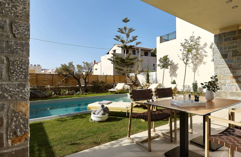 Outdoor dining table on the 4BR Villa patio beside the lawn, sun loungers and private pool in Gouves
