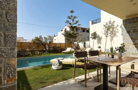 Outdoor dining table on the 4BR Villa patio beside the lawn, sun loungers and private pool in Gouves