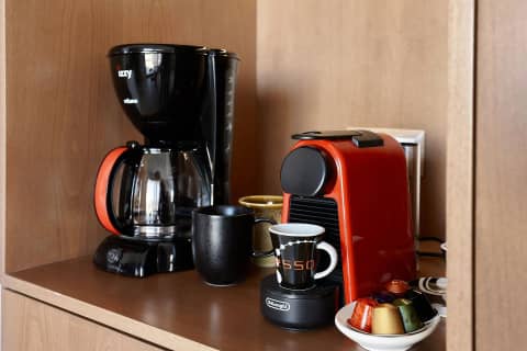 Coffee corner with filter coffee maker, espresso machine and capsules in the suite kitchen cabinet