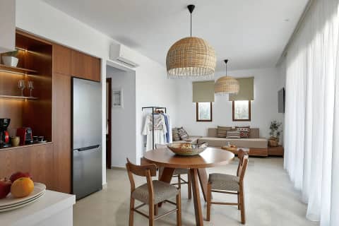 Open plan living room with corner sofa, woven pendant lights, dining table and clothes rail