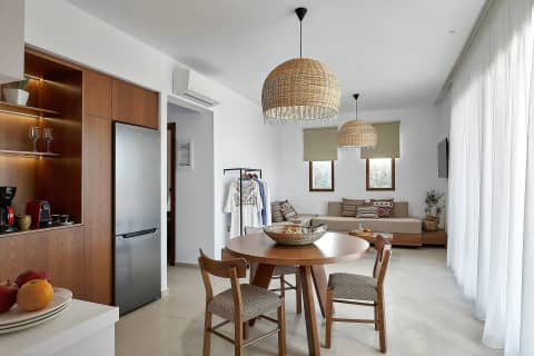 Wide view of the suite open plan living room with dining table, corner sofa and sheer curtains
