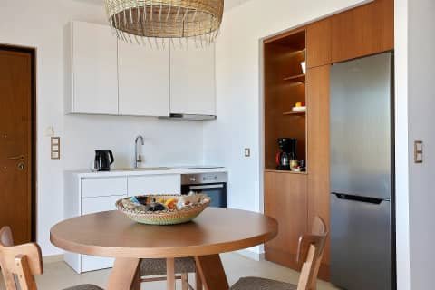 The white kitchen of the suite with kettle, sink, oven and a welcome bowl on the round dining table