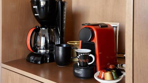 Filter coffee maker and espresso machine with mugs and capsules on the wooden kitchen shelf
