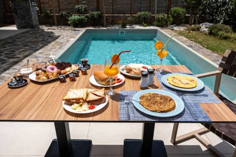 Breakfast table set by the private pool with omelettes, sandwiches, pastries and fresh juices at Volta Suites, Gouves