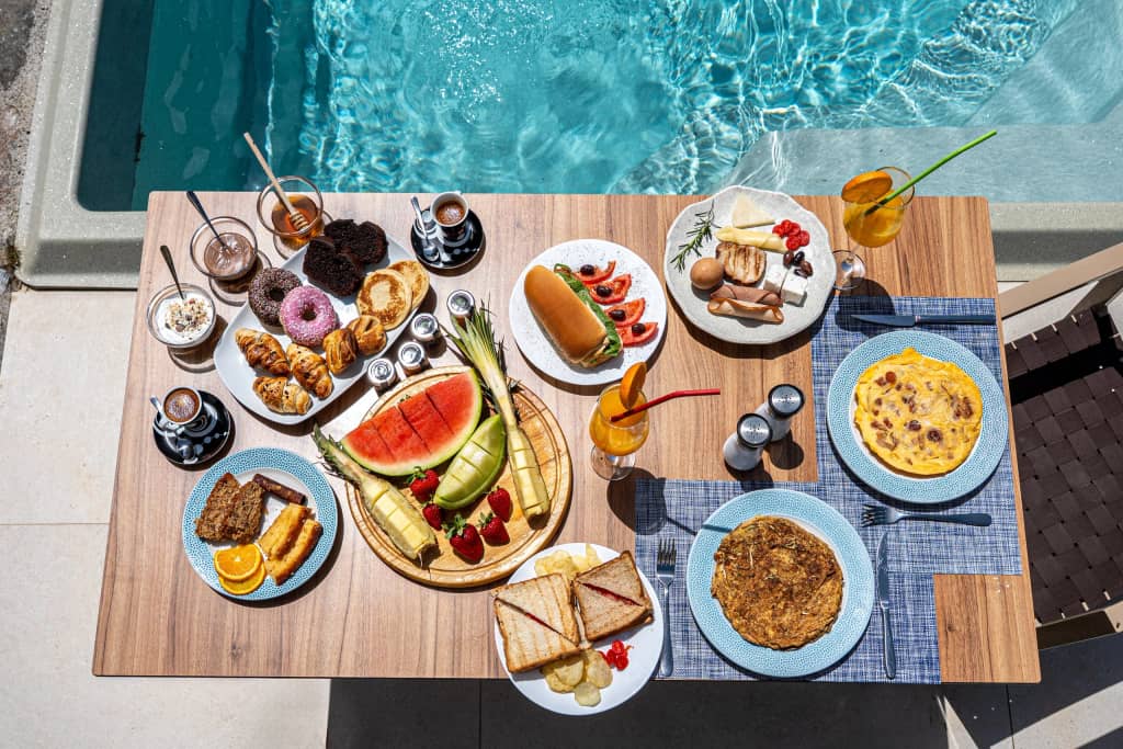Rich Cretan breakfast spread served on a table beside the pool at Volta Suites and Villas