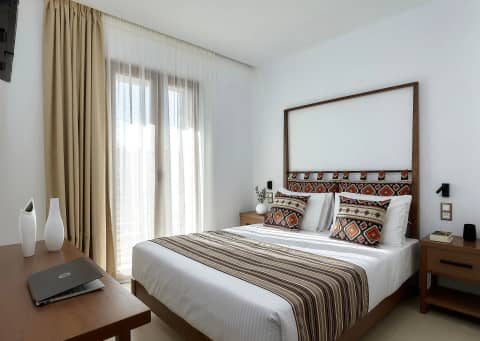 Bedroom of the One-Bedroom Suite with double bed, patterned kilim cushions and sheer curtains to the private garden
