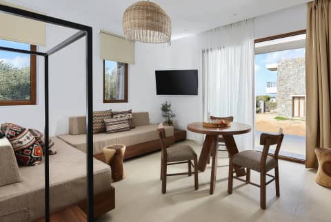 One-bedroom suite living room with twin daybeds, kilim cushions and glass doors to the sunlit courtyard