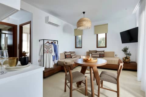One Bedroom Suite living area with daybed sofa, round dining table, rattan pendant lamp and Cretan textiles